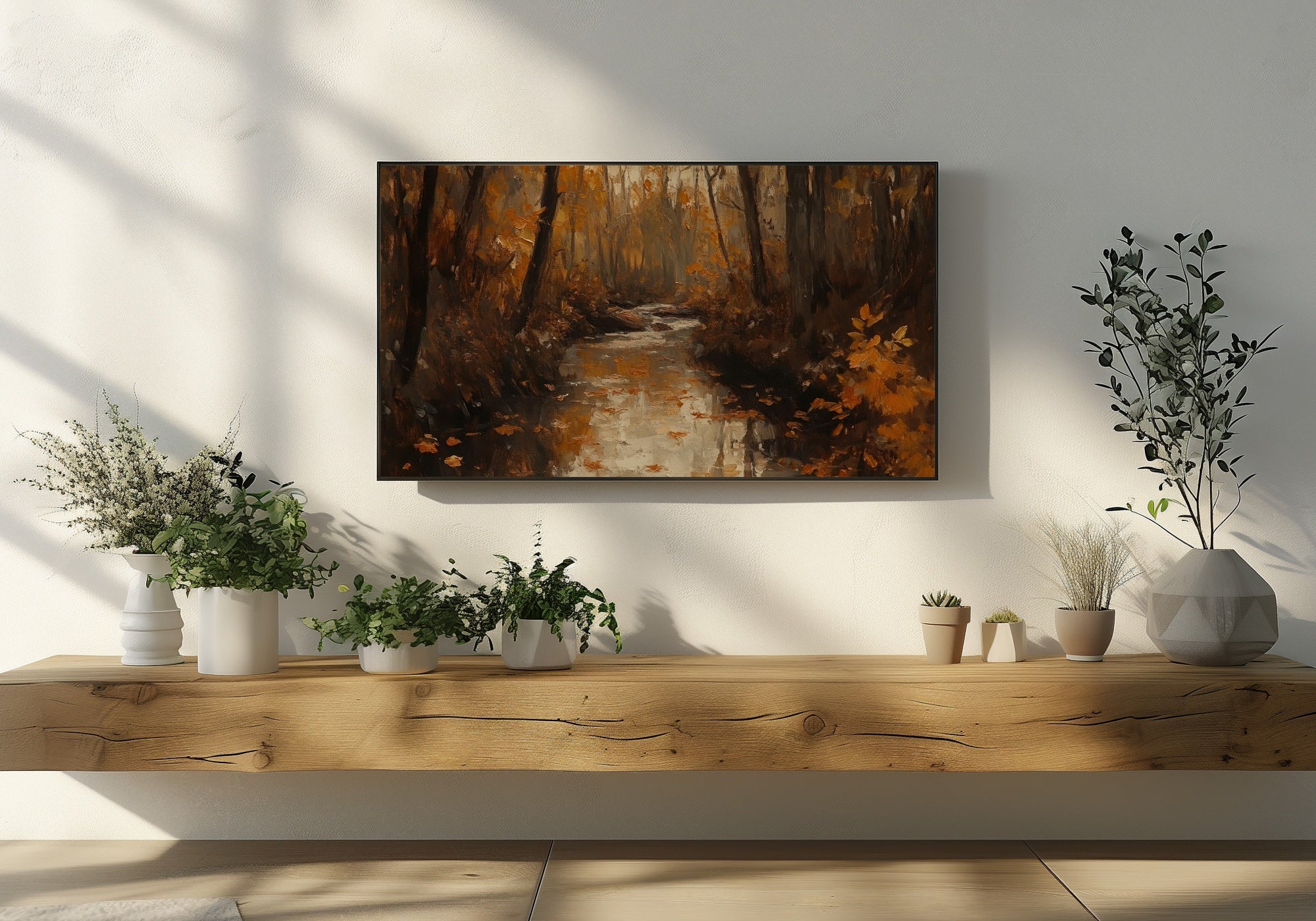 Fall Frame TV Art featuring a warm autumn forest scene with golden leaves and a reflective stream, displayed above a rustic wooden console with potted plants in soft natural light