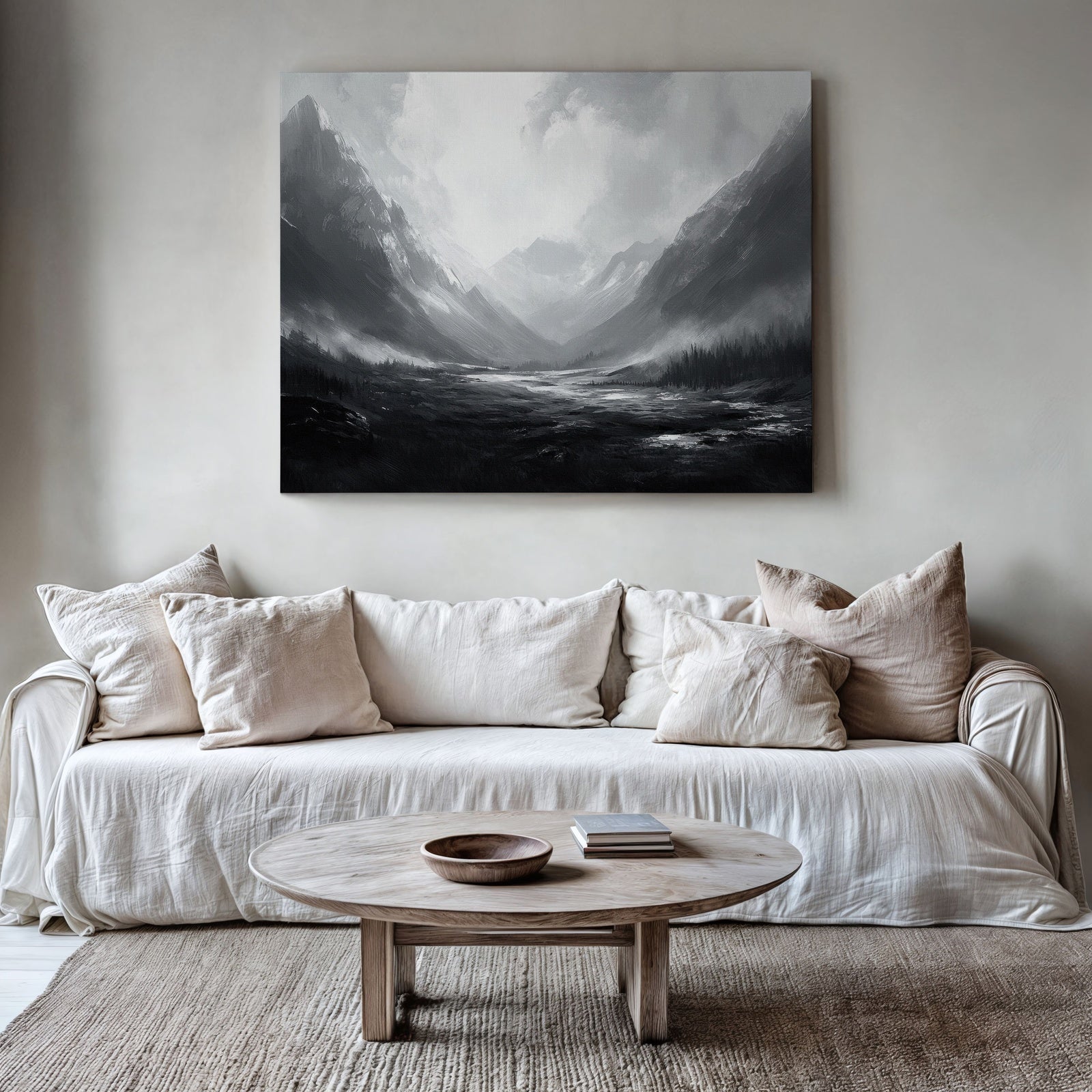 Neutral printable wall art featuring a black and white mountain landscape with dramatic light and misty atmosphere, displayed above a beige sofa in a minimalist living room