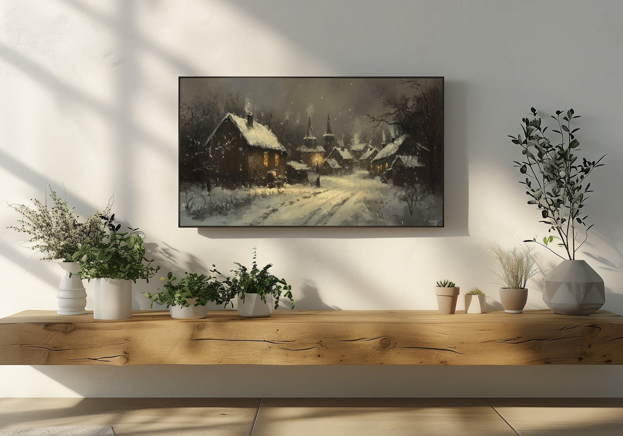 Winter landscape artwork displayed on a Samsung Frame TV, featuring a snowy village with warmly lit cottages and a peaceful night atmosphere, styled in a cozy modern living room with wooden shelf and plants