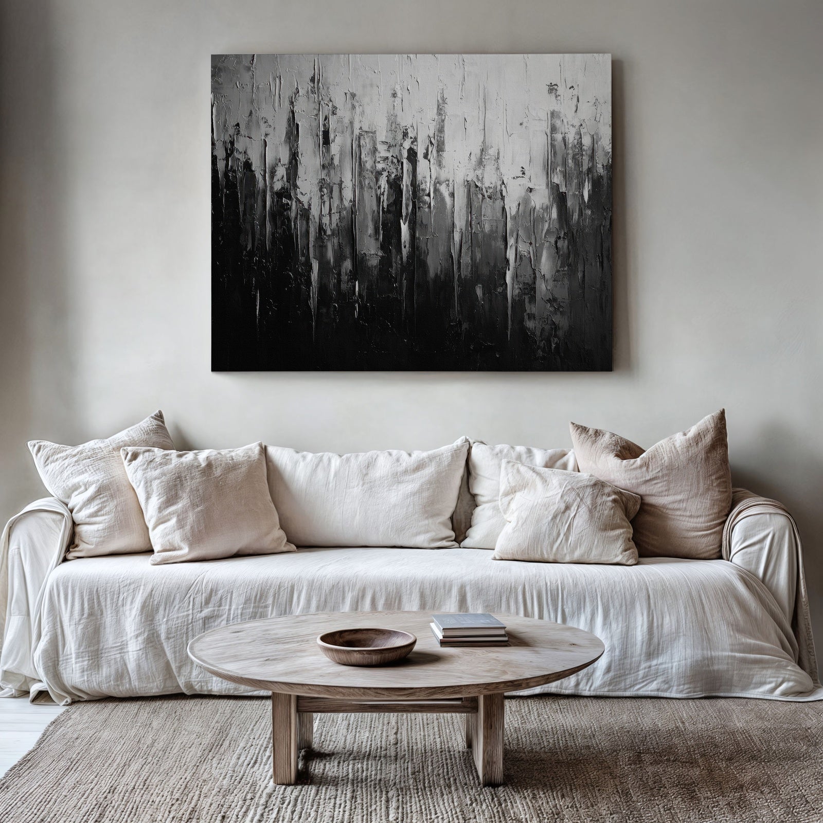 Abstract printable wall art in black and white tones featuring textured vertical brushstrokes, displayed above a neutral beige sofa with cozy pillows in a modern minimalist living room