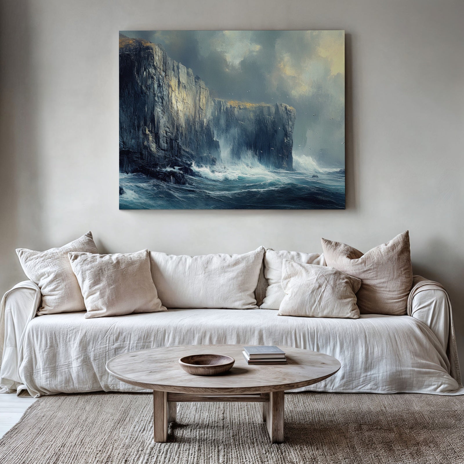 A serene coastal cliff landscape with dramatic waves crashing against tall, rugged rock formations, displayed as wall art above a neutral modern sofa in a calming, minimalist living room